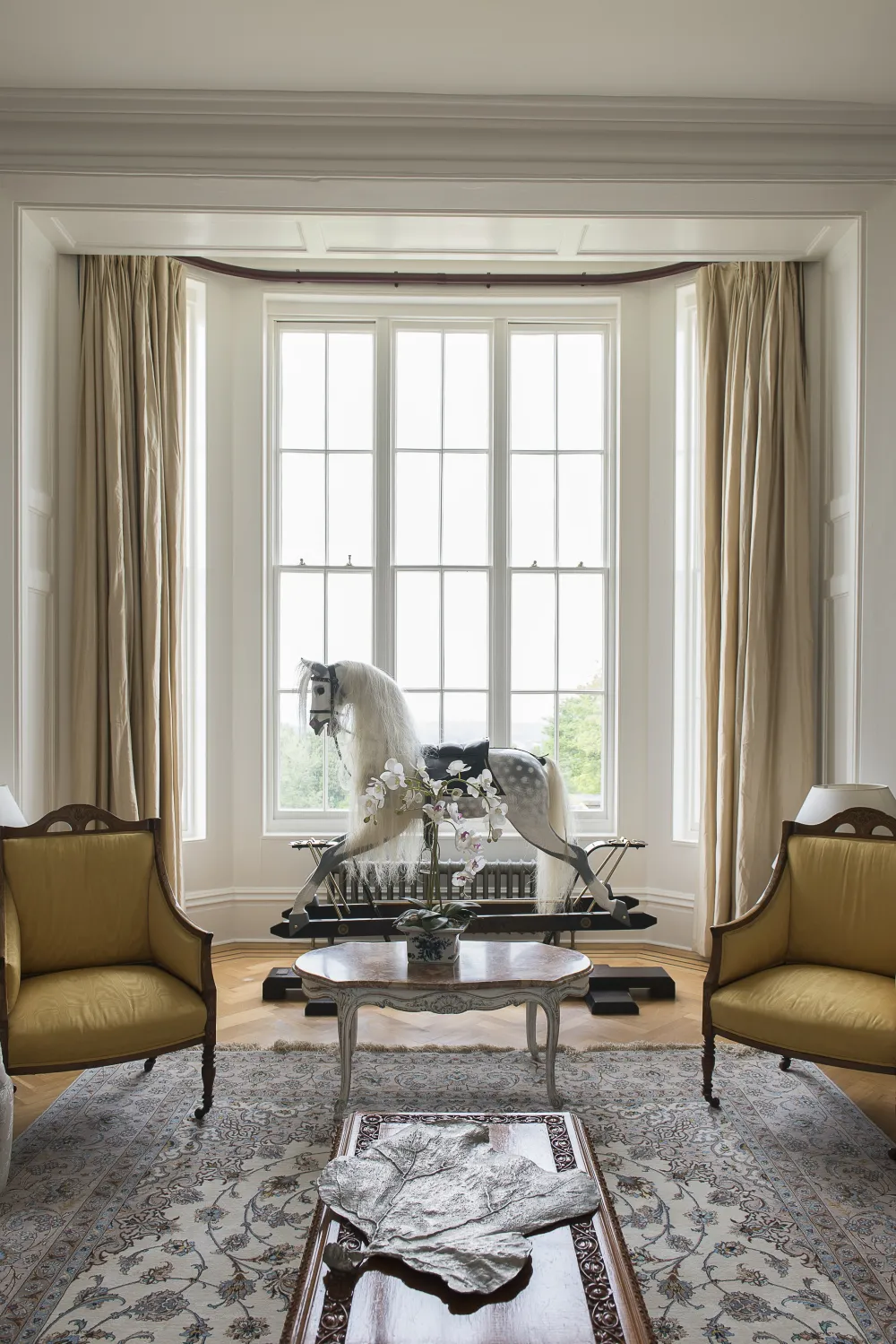 Rocking horse in bay window with full length curtains